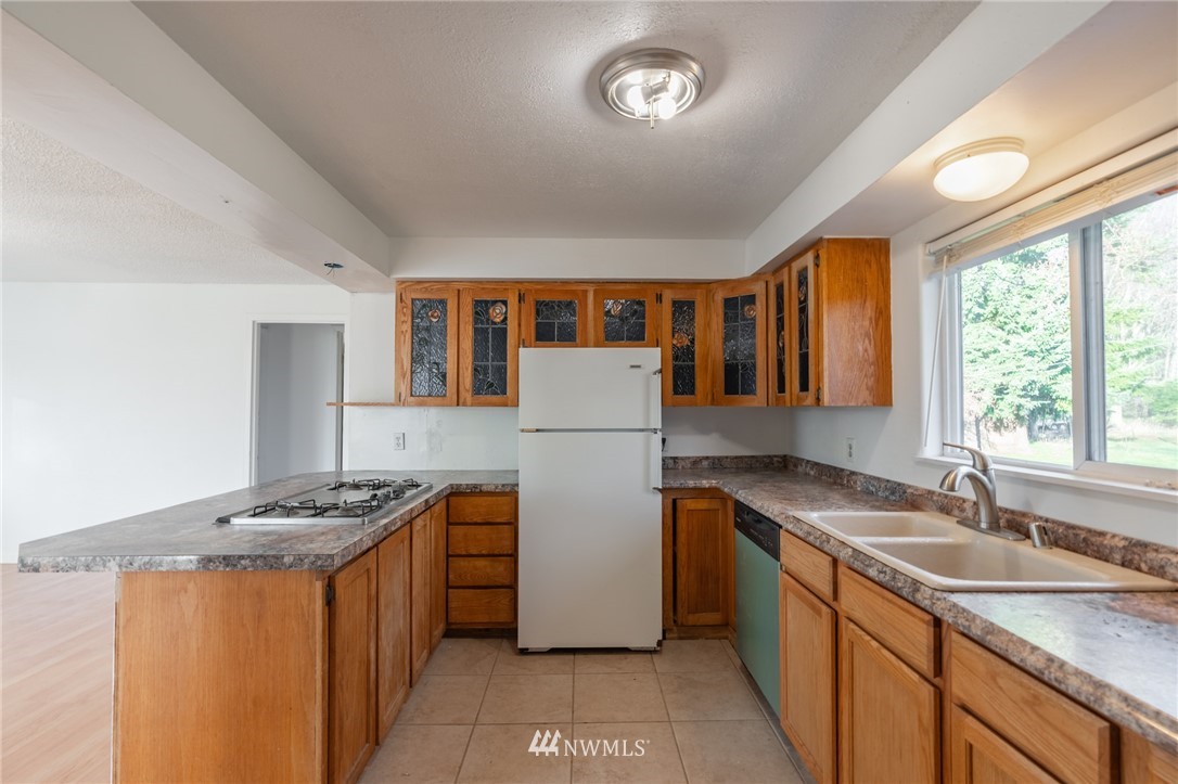 7370 Enterprise Road Ferndale, WA 98248 - Photo 7 of 25 a kitchen with stainless steel appliances granite countertop a refrigerator a sink dishwasher a stove and a dining table with wooden floor