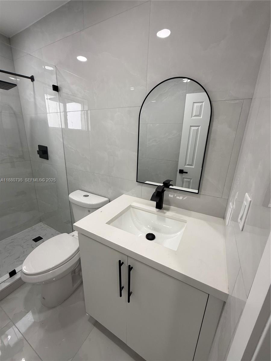 841 West 50th Street, Unit 2 Hialeah, FL 33012 - Photo 5 of 12 a bathroom with a toilet a sink and mirror