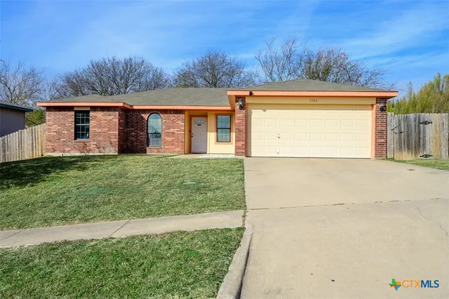 a front view of house with yard and trees in the background