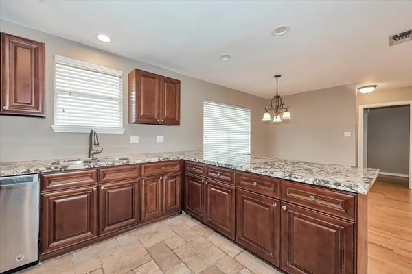 a large kitchen with granite countertop a sink and cabinets
