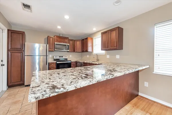 a kitchen with stainless steel appliances granite countertop a refrigerator stove top oven and a sink with large window