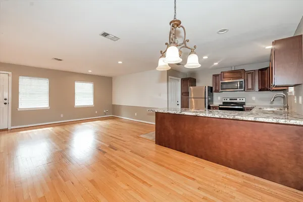 a kitchen with stainless steel appliances granite countertop a refrigerator a stove top oven a sink dishwasher and wooden floor
