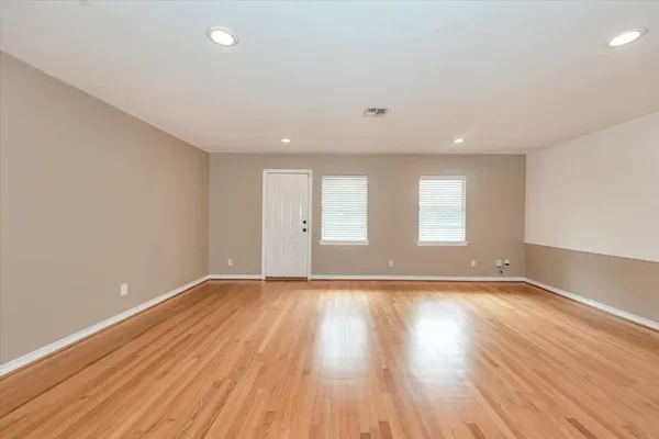 a view of an empty room with wooden floor and window