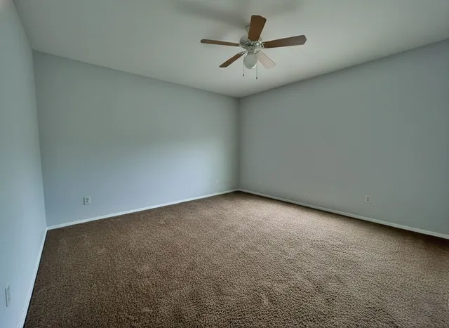 an empty room with a ceiling fan and wooden floor