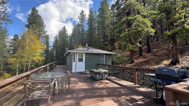 a view of a patio with table and chairs under an umbrella with large trees