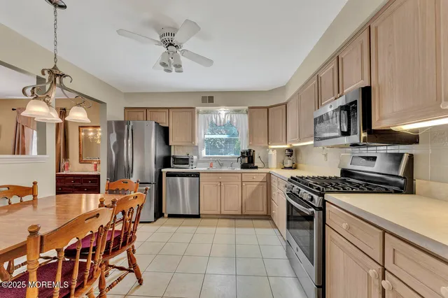 a kitchen with stainless steel appliances granite countertop a stove top oven a refrigerator a sink dishwasher a dining table and chairs with wooden floor