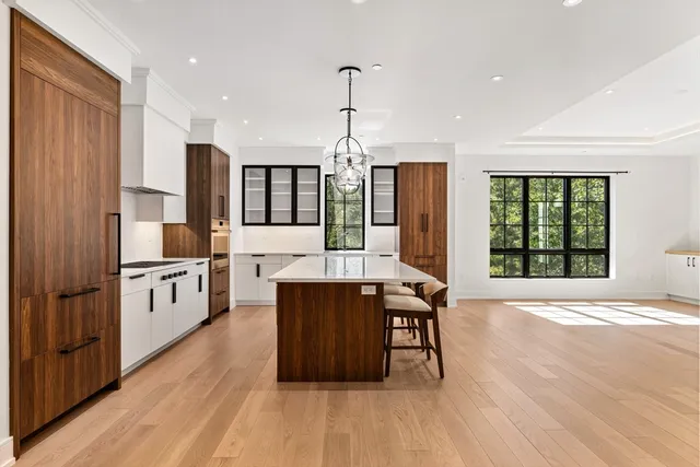 a kitchen with stainless steel appliances granite countertop a stove a sink dishwasher a refrigerator and a dining table with wooden floor