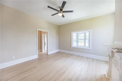an empty room with wooden floor ceiling fan and windows
