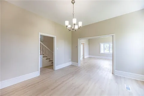 a view of a room with wooden floor chandelier and a kitchen