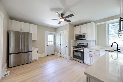 a kitchen with granite countertop a refrigerator oven a sink dishwasher and a stove with wooden floor