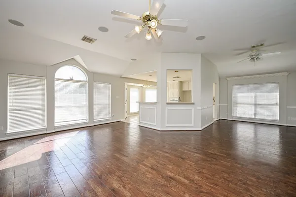 a view of an empty room with a window and wooden floor