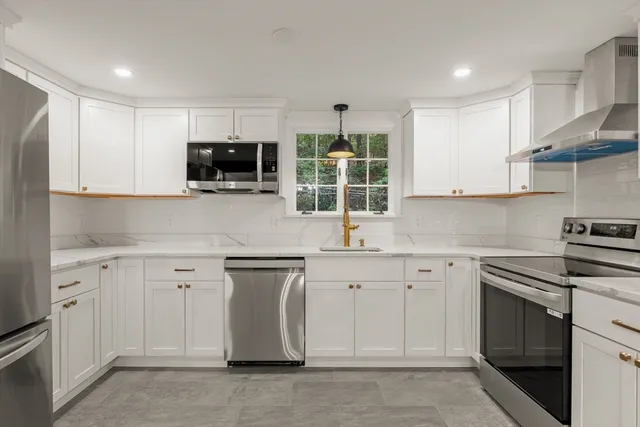 a kitchen with white cabinets and appliances