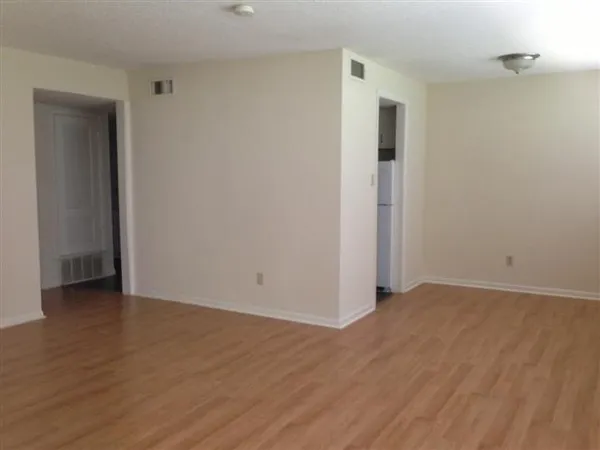 a view of an empty room with wooden floor and closet