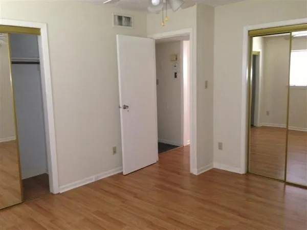 an empty room with wooden floor & closet area