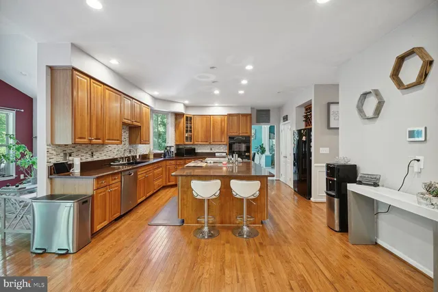 a kitchen with stainless steel appliances granite countertop wooden cabinets a sink dishwasher a stove and a refrigerator with wooden floor