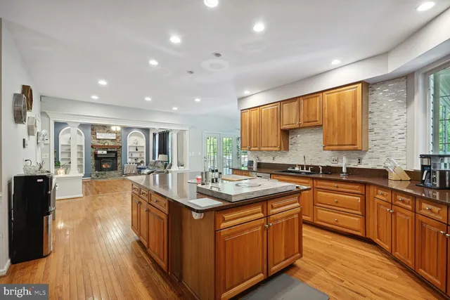 a kitchen with stainless steel appliances granite countertop wooden cabinets a sink dishwasher a stove and a refrigerator with wooden floor