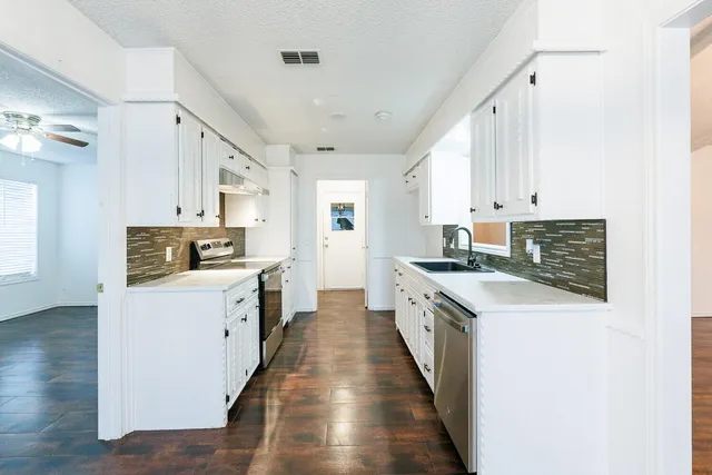 a kitchen with sink stove and cabinets