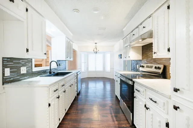 a kitchen with granite countertop white cabinets and white appliances