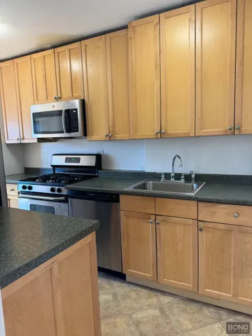 a kitchen with stainless steel appliances granite countertop a stove a sink and a microwave