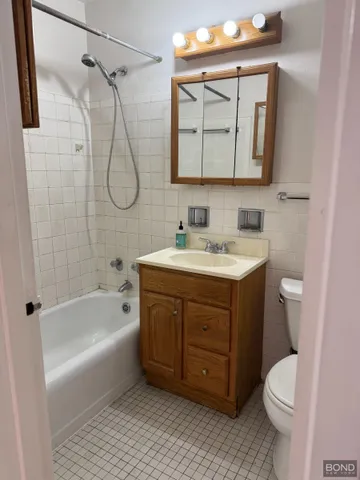a bathroom with a sink vanity mirror bathtub and toilet