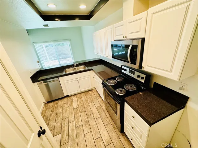 a kitchen with granite countertop a sink a stove and cabinets