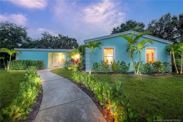 a front view of a house with a yard and potted plants