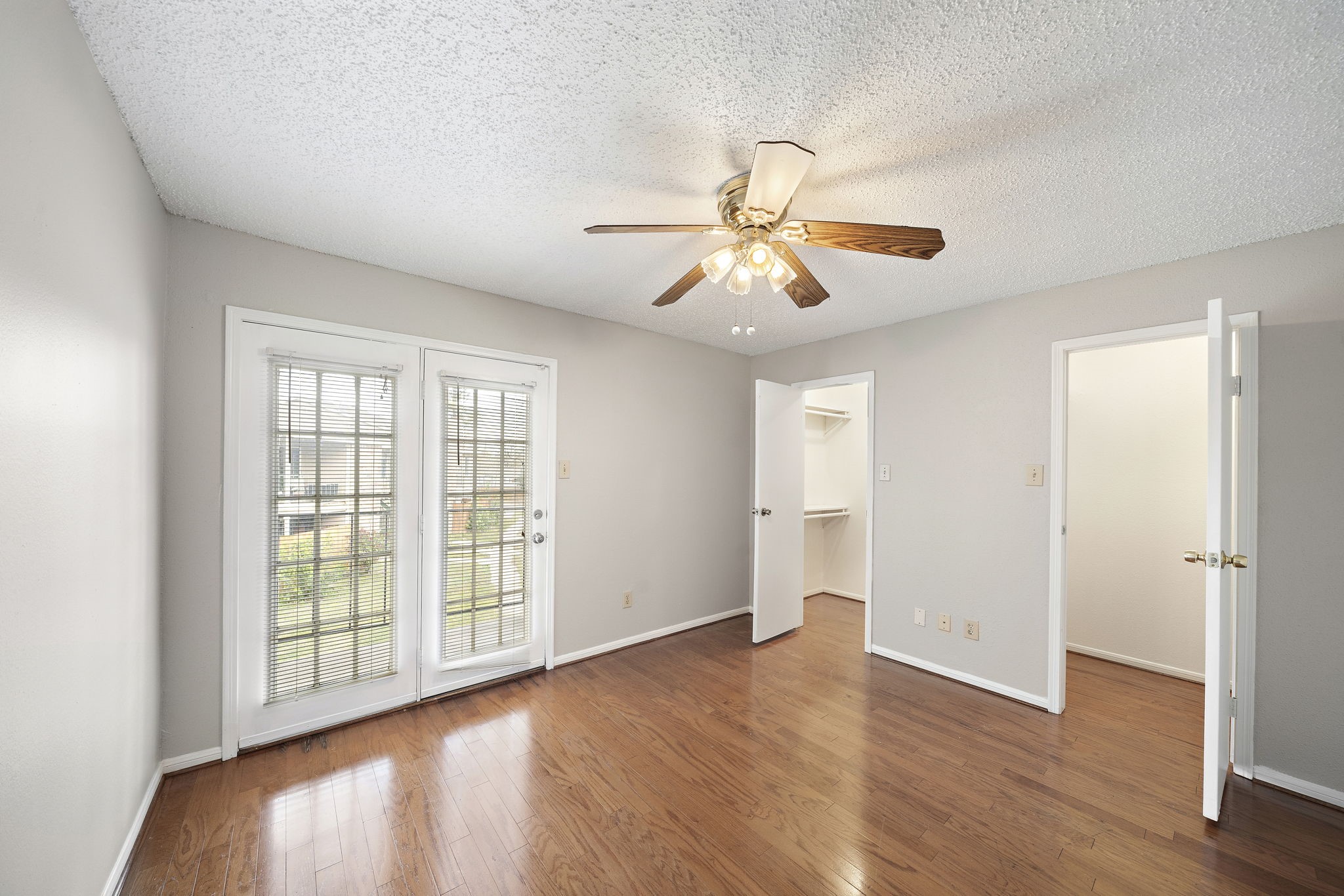 a view of an empty room with a window and wooden floor