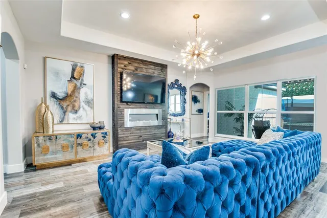 a living room with furniture a chandelier and a flat screen tv