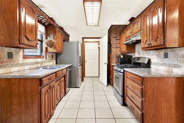 a kitchen with stainless steel appliances granite countertop a refrigerator a sink dishwasher and wooden cabinets with wooden floor