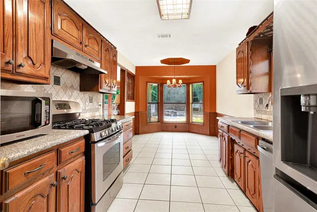 a kitchen with stainless steel appliances granite countertop a stove a sink and a microwave