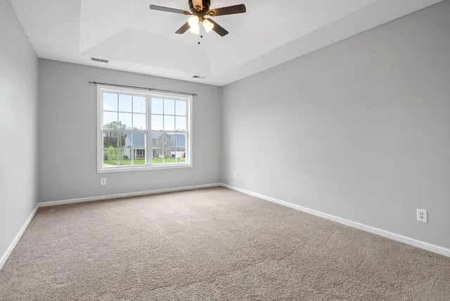 an empty room with windows and ceiling fan