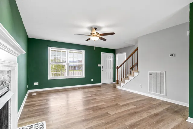 a view of an empty room with a window and wooden floor