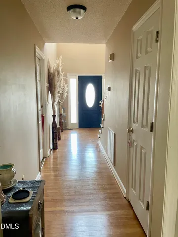 a view of a hallway to a livingroom with furniture wooden floor and window