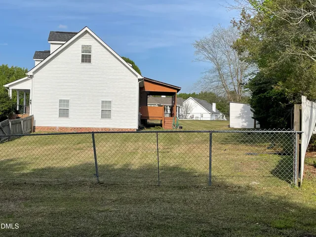a view of a white house next to a yard with a large tree