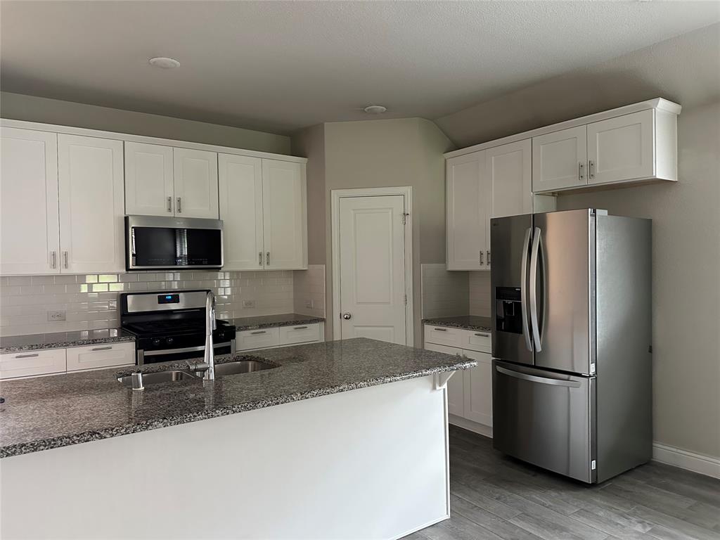 2708 Country Church Road McKinney, TX 75071 - Photo 5 of 17 a kitchen with granite countertop a refrigerator and a sink