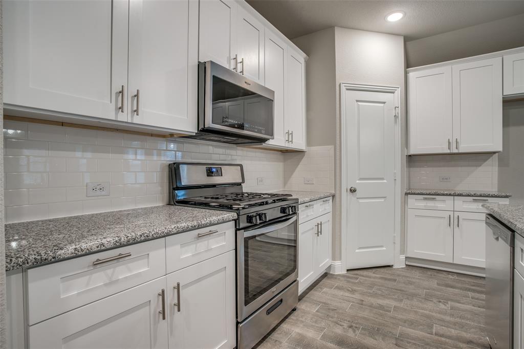 2708 Country Church Road McKinney, TX 75071 - Photo 5 of 12 a kitchen with granite countertop white cabinets and stainless steel appliances