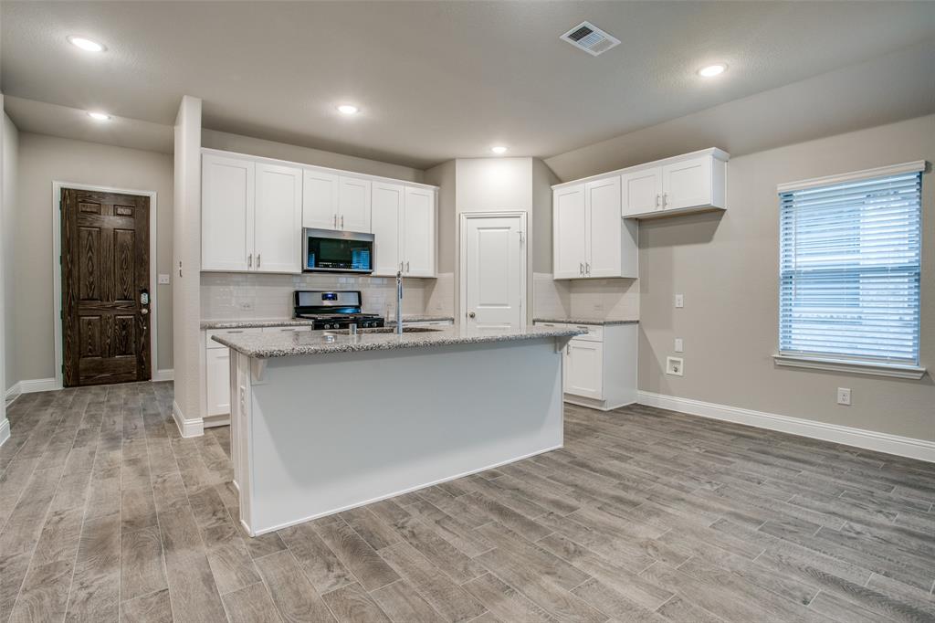 2708 Country Church Road McKinney, TX 75071 - Photo 6 of 12 a large kitchen with stainless steel appliances granite countertop a stove a sink and a microwave