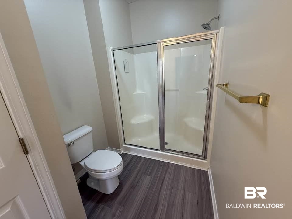 2651 South Juniper Street, Unit 401 Foley, AL 36535 - Photo 26 of 27 Bathroom featuring toilet, a shower stall, and wood finished floors