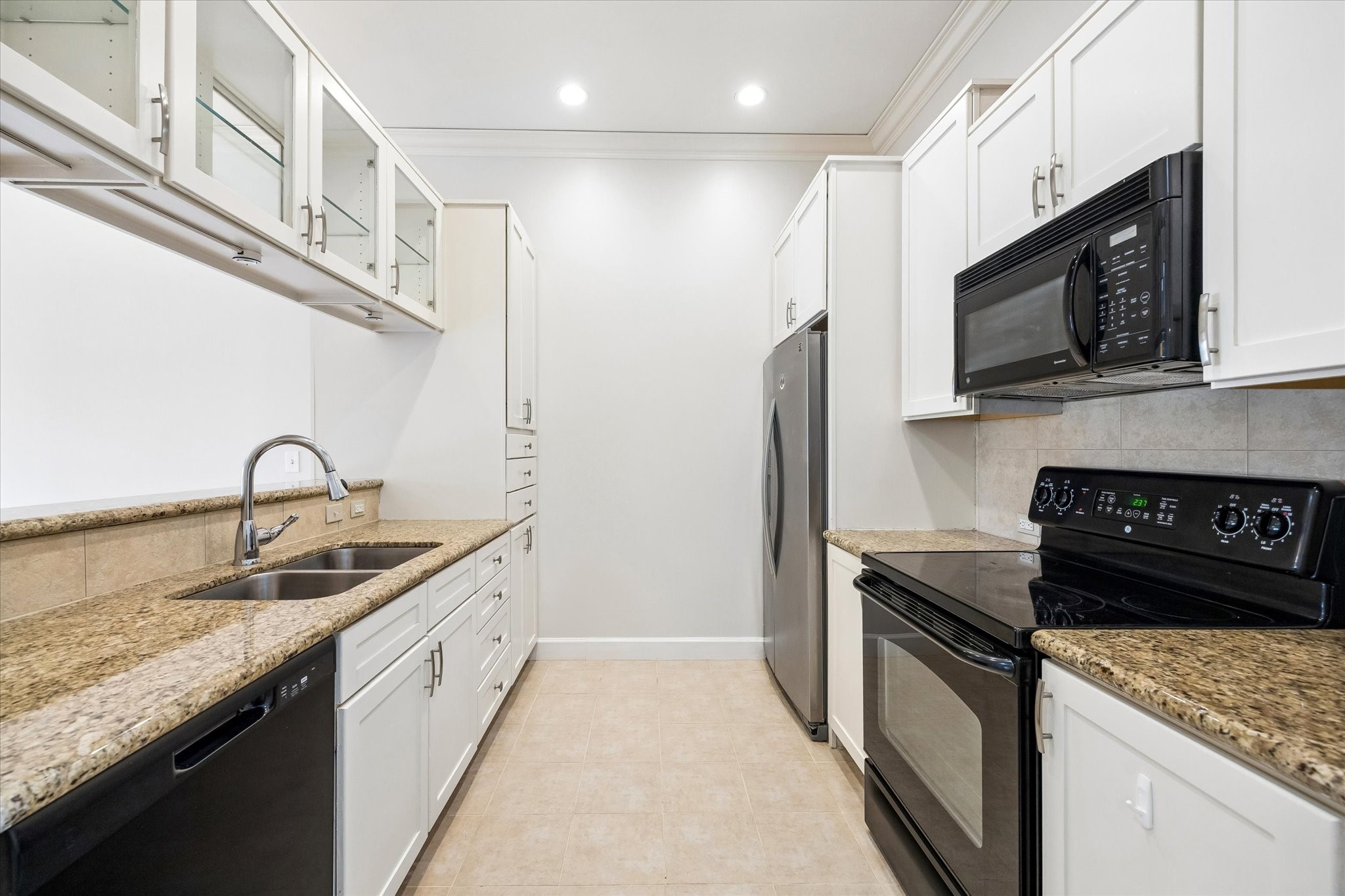 100 Willard Street, Unit 15 Houston, TX 77006 - Photo 8 of 25 The galley style kitchen features granite countertops, stainless appliances, tile flooring, abundant cabinetry, and glass display cabinets for added character and storage.
