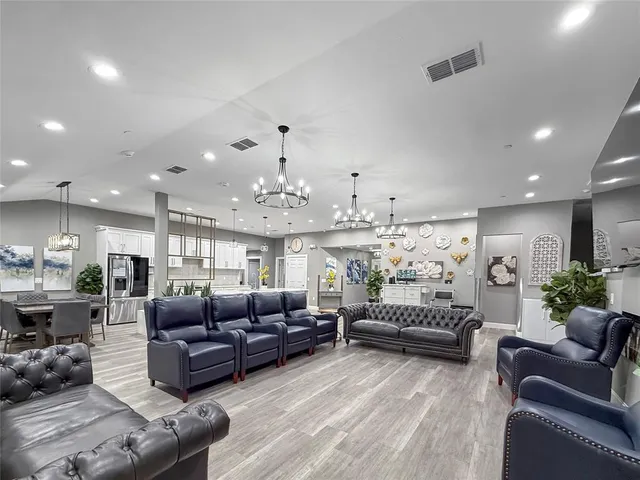 a living room with furniture kitchen view and a chandelier