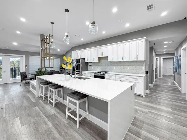 a large kitchen with kitchen island a stove a sink a refrigerator and a dining table with wooden floor