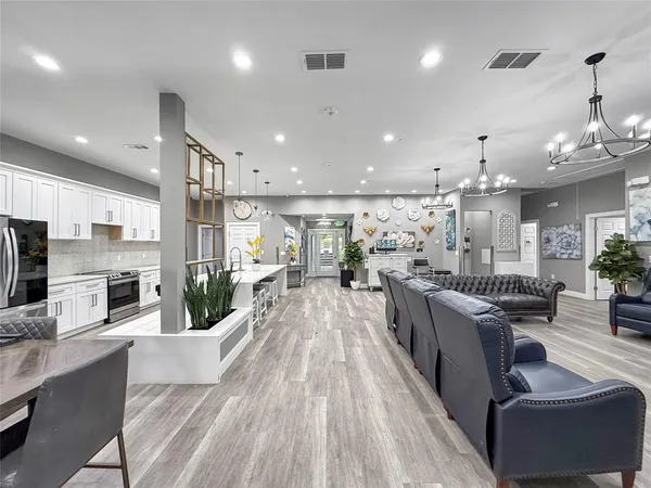 a view of a kitchen with kitchen island stainless steel appliances refrigerator stove microwave oven dining table and chairs