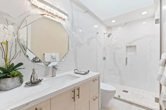 a bathroom with a granite countertop sink a toilet a mirror and shower