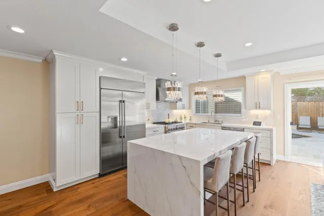 a large kitchen with kitchen island a large counter top space and stainless steel appliances