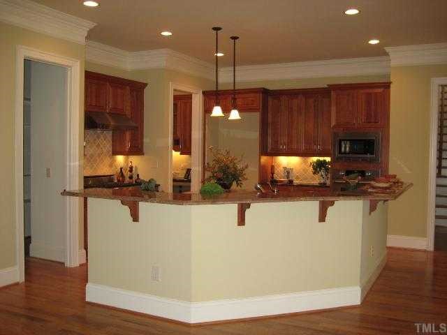3226 Rain Forrest Way Raleigh, NC 27614 - Photo 4 of 12 This view of the kitchen showcases the beautiful custom crown molding, large raised granite counter top. View of the back stairwell that leads to the bonus on right. Cherry cabinets, under cabinet lighting & recessed lights add to warmth. Pantry on left.