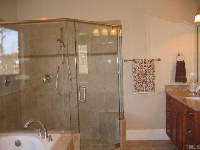 3226 Rain Forrest Way Raleigh, NC 27614 - Photo 9 of 12 The Owner's Suite Bath has 2 separate raised cherry vanities, a large tiled shower w/2 heads & seat, tile surround jetted tub and a linen closet.