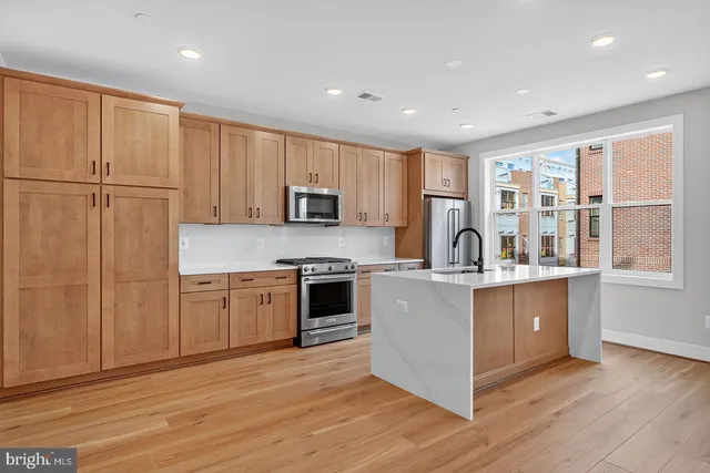 a large kitchen with stainless steel appliances granite countertop a stove a sink dishwasher and a refrigerator with wooden floor