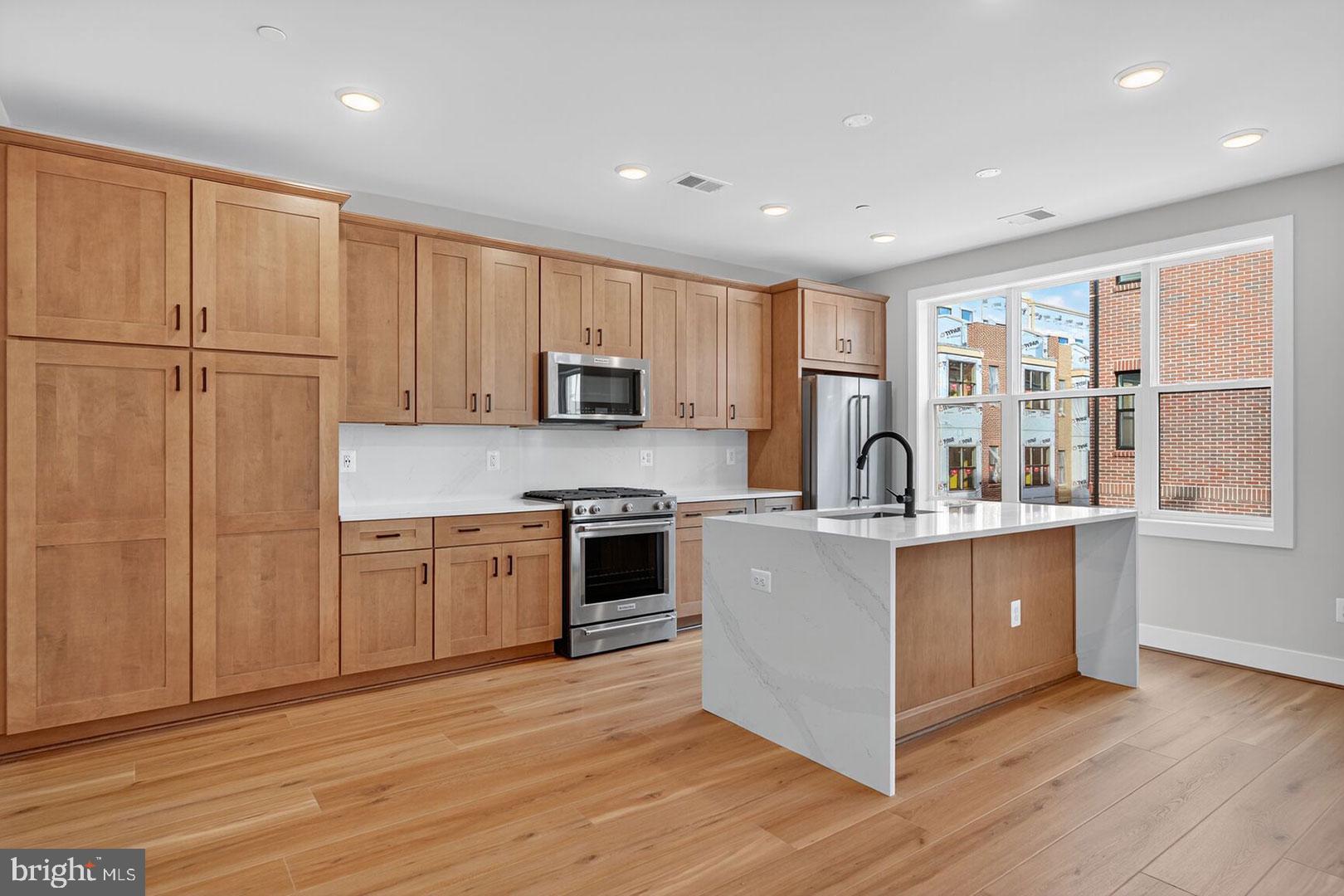 a large kitchen with stainless steel appliances granite countertop a stove a sink dishwasher and a refrigerator with wooden floor