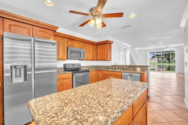 a kitchen with stainless steel appliances kitchen island granite countertop a refrigerator a stove top oven a sink dishwasher and dining table with wooden floor