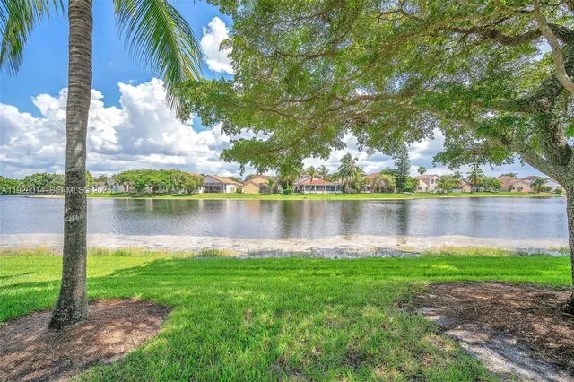 a lake view with a big yard and palm trees